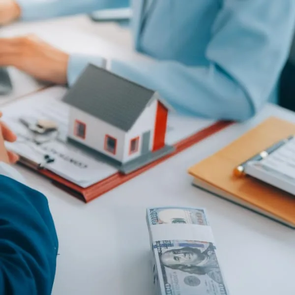 Liasse de billets et modèle de maison sur un bureau lors d'une transaction de prêt instantané