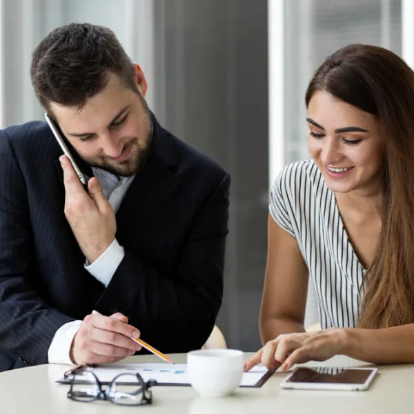 Conseiller et cliente consultant des documents sur tablette et téléphone pour planifier un remboursement de prêt flexible