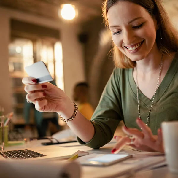 Femme utilisant son téléphone et une carte bancaire pour effectuer une demande de prêt rapide en ligne