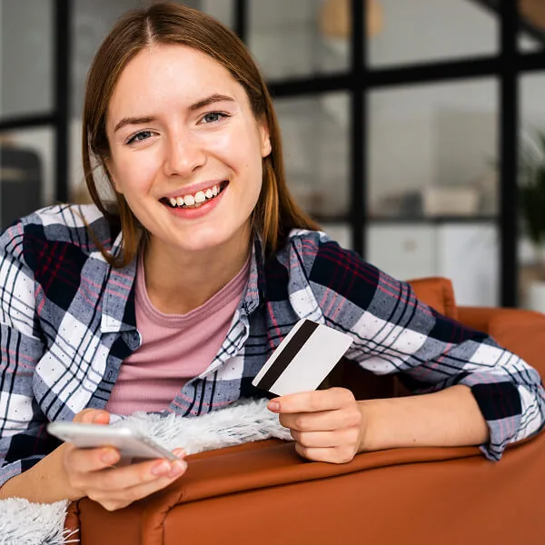 Jeune femme utilisant une carte bancaire et un téléphone illustrant les personnes pouvant bénéficier d’un prêt rapide en ligne
